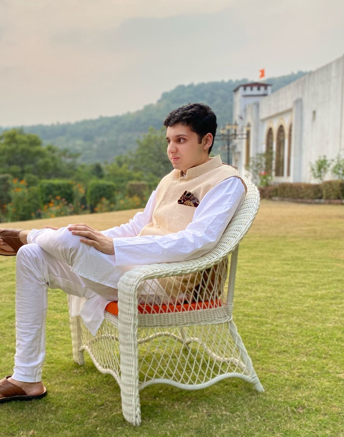 Seated on a lawn below a hill fort