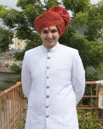 In a white sherwani and red pheta