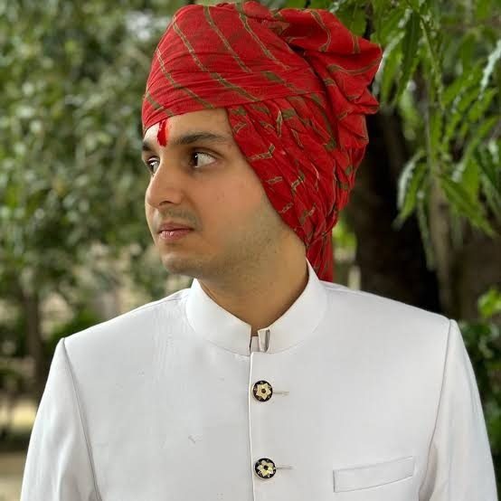 In a red pheta and white sherwani